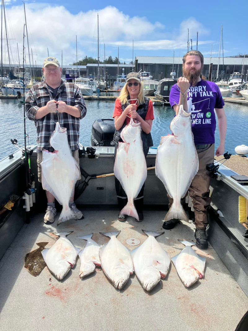 Group of anglers displaying several Pacific halibut at a Newport, Oregon marina after a productive recreational halibut fishing trip